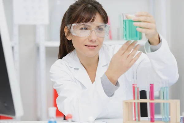 Frau blickt im Labor auf ein Reagenzglas — Stockfoto