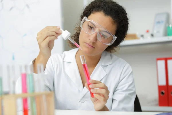 Femme sérieuse avec pipette en laboratoire — Photo