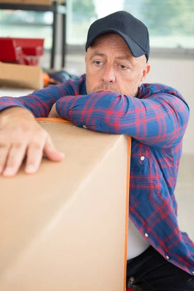 Hombre cansado durante el movimiento y embalaje cajas de cartón — Foto de Stock