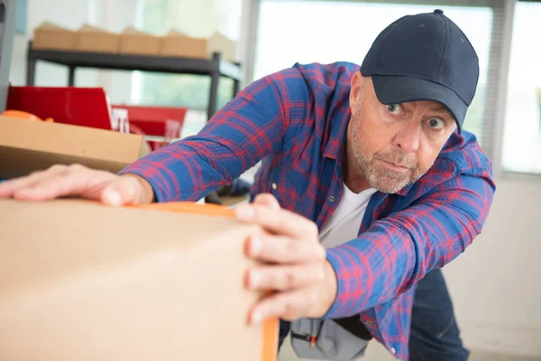 A man is moving a heavy box — Stock Photo, Image