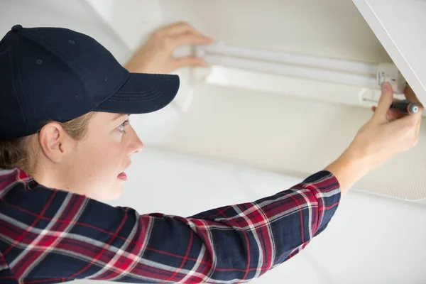 Woman fixing broken lamp — Stock Photo, Image