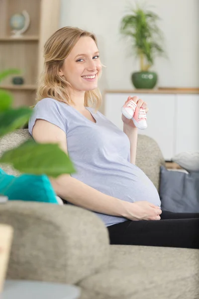 Schwangere auf Sofa mit rosa Schuhen — Stockfoto