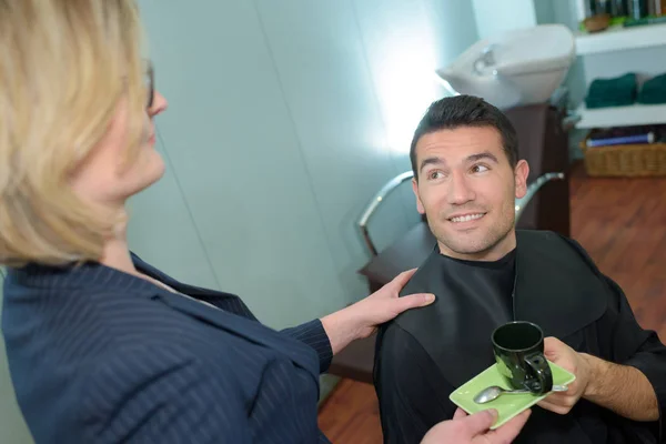 Glücklicher Mann trinkt Kaffee beim Friseur — Stockfoto