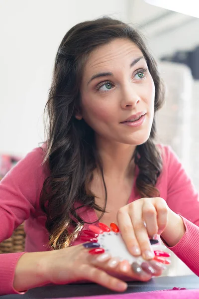 Frau im Nagelstudio wählt Farbe des Nagellacks — Stockfoto