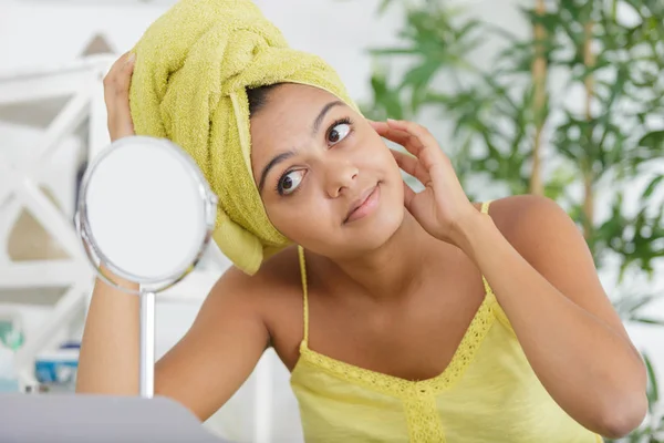 Vrouw met een handdoek kijken in de spiegel — Stockfoto