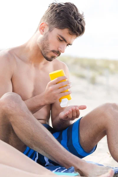 Mann versprüht Sonnencreme am Strand — Stockfoto