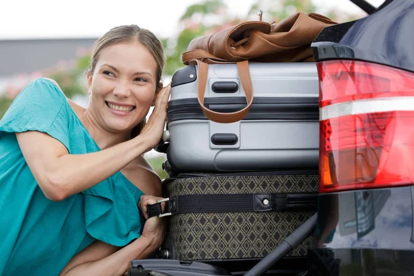 Женщина толкает багаж в багажнике автомобиля — стоковое фото
