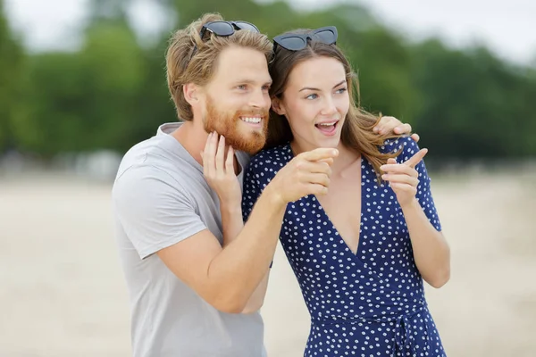 Casal apontando para o mar — Fotografia de Stock