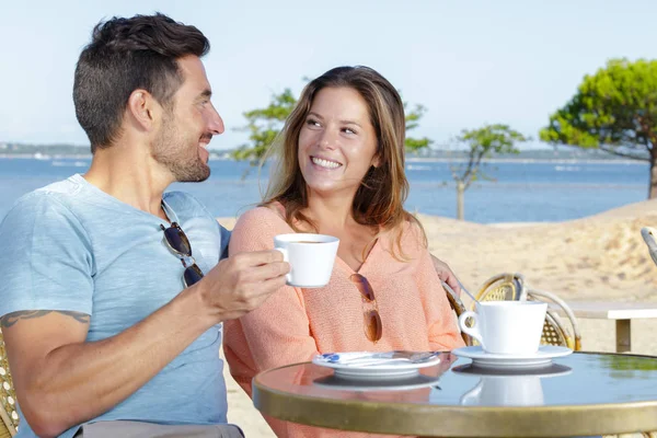 Couple having a coffee near the sea — Stock Photo, Image