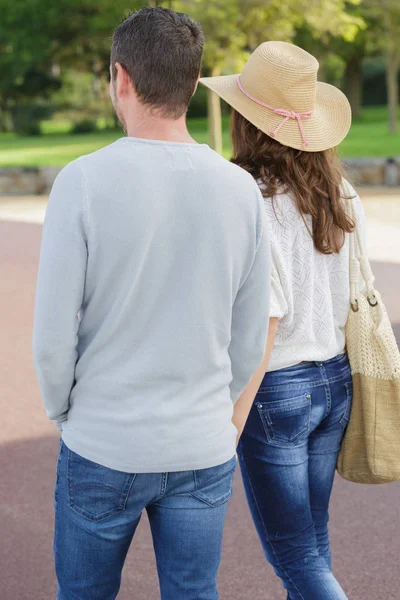 Rückansicht eines jungen Paares, das in einem Park spaziert — Stockfoto