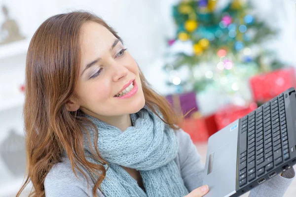 Mooie jonge vrouw zitten op de bank met laptop computer glimlachen — Stockfoto