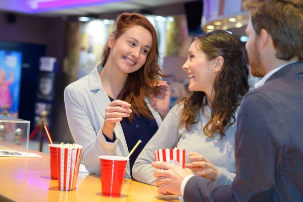 Happy friends buying popcorn and refreshments in the cinema — 스톡 사진
