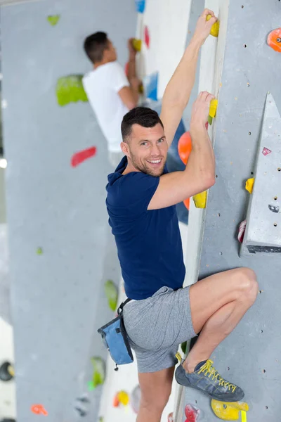 Atletický muž lezení na vnitřní lezecké stěně — Stock fotografie