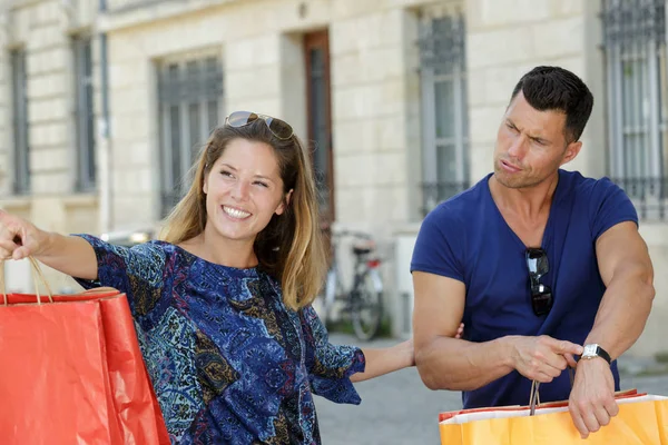 Novio mostrando el tiempo a shopaholic socio — Foto de Stock