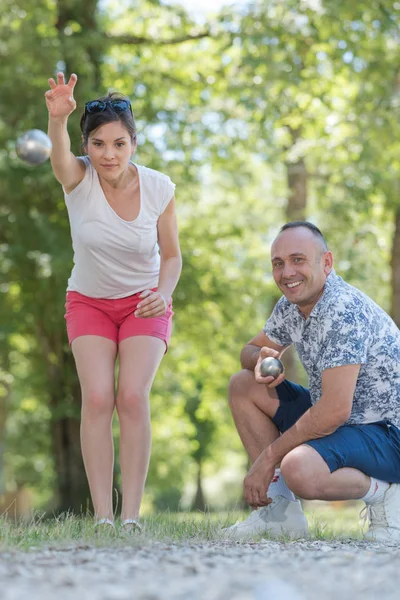 Koppel van middelbare leeftijd spelen petanque bal midden in de lucht — Stockfoto