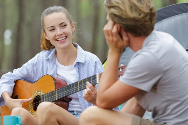 Donna che suona la chitarra vicino al falò al campeggio — Foto Stock