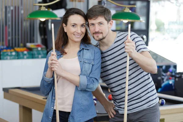 Feliz pareja con bolas de billar y una señal de billar sonriendo — Foto de Stock