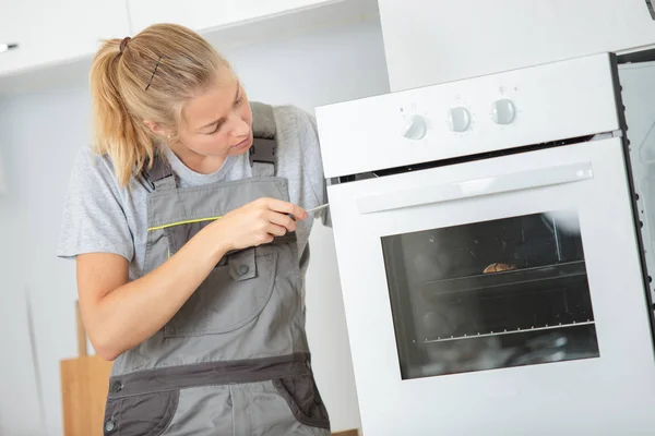 Reparadora mulher que fixa um forno clientes — Fotografia de Stock