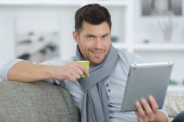 Retrato do homem em casa segurando bebida e tablet digital — Fotografia de Stock