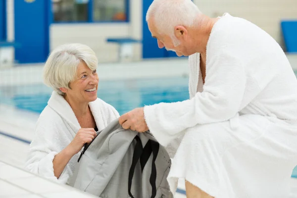 上了年纪的夫妇在有游泳池的保暖处放松一下 — 图库照片