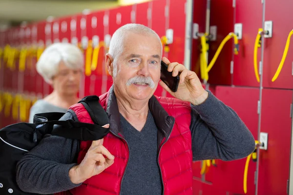 Homem sênior usando telefone no vestiário — Fotografia de Stock