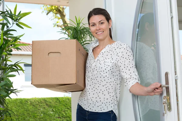 Kobieta trzyma kartonowe pudełko w drzwiach nieruchomości — Zdjęcie stockowe