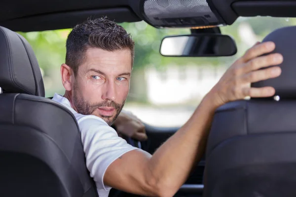 Motorista girando em seu assento para olhar para trás para reverter — Fotografia de Stock