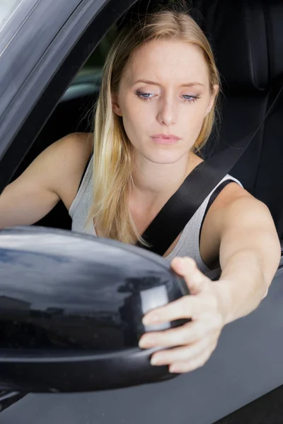 Vrouw aanpassen zijspiegel van blauwe auto in de natuur — Stockfoto
