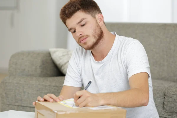 Junger Mann schreibt Portemonnaie für Paket — Stockfoto