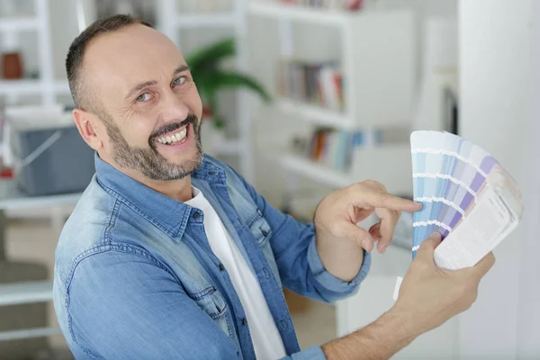 Hombre apuntando hacia la muestra de color de la pintura y riendo — Foto de Stock