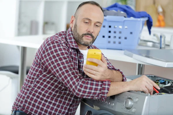 Serviceman med multimeter på tvättmaskin — Stockfoto