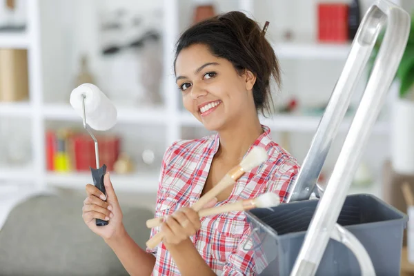 Jong gelukkig vrouw schilderij interieur muur — Stockfoto