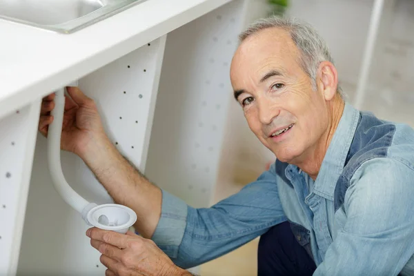 Idősebb férfi illeszkedik a mosogató csövek — Stock Fotó