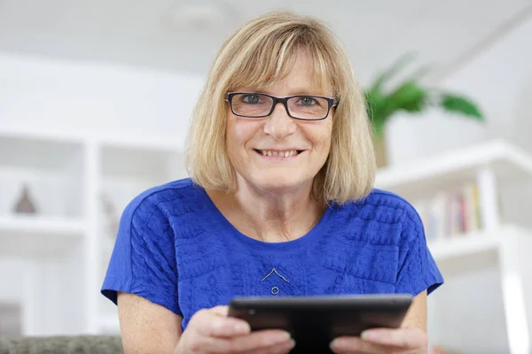 Mulher madura em casa trabalhando com um tablet — Fotografia de Stock