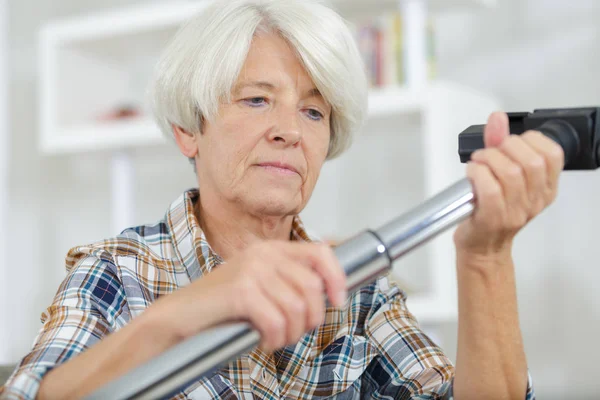 Starší žena, vysávání koberců — Stock fotografie