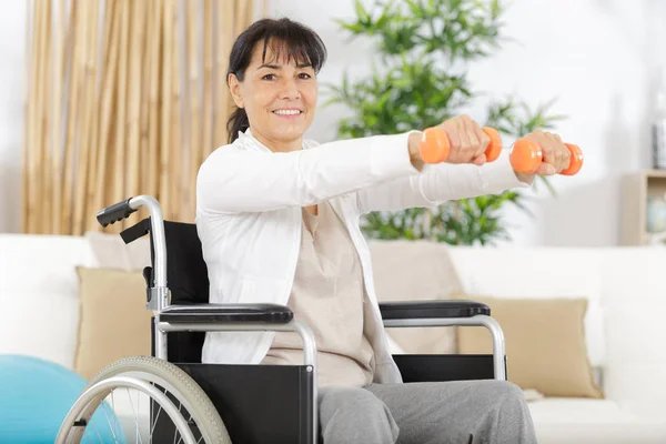 Donna anziana in sedia a rotelle esercizio di esecuzione con manubrio — Foto Stock
