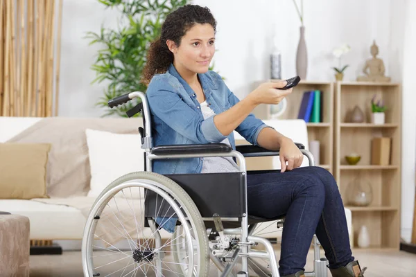 Woman in wheelchair using remote control — Stock Photo, Image