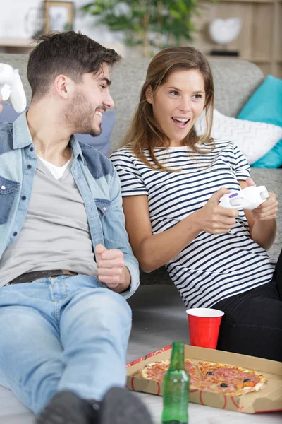 Pareja joven con cerveza y pizza jugando videojuegos en casa —  Fotos de Stock