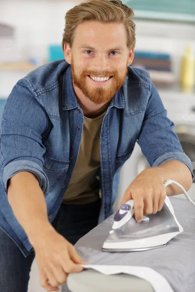 Feliz joven planchado en casa — Foto de Stock