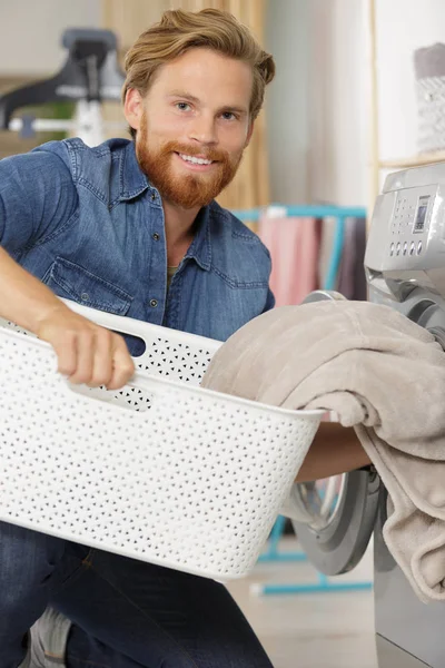 Happy man taking clothes from drying machine — Stock Photo, Image