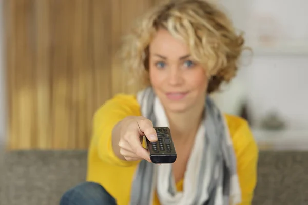 Mujer con control remoto de tv en sofá — Foto de Stock