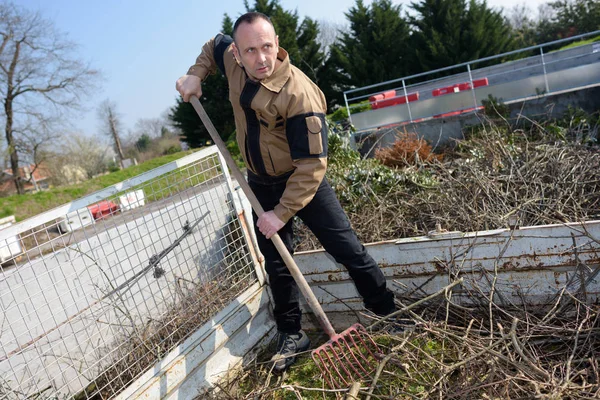 Homme ratissant des feuilles dans le jardin — Photo