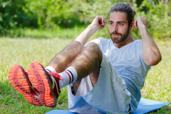 Young sportsman doing abdominal crunches outdoors — Stock Photo, Image