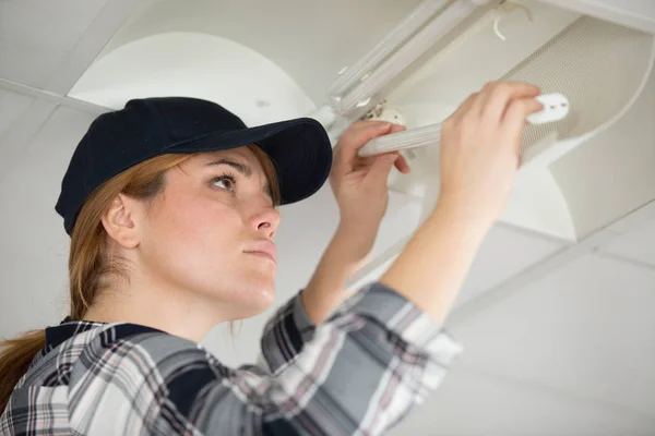 Kvinna ersätter glödlampa hemma — Stockfoto