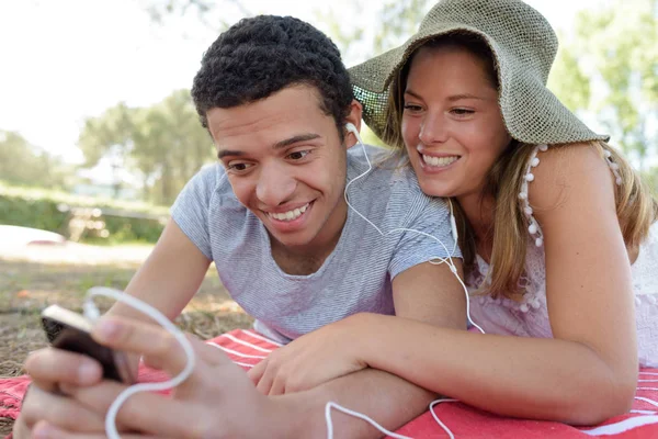 Encantadora pareja que pone música en los auriculares — Foto de Stock