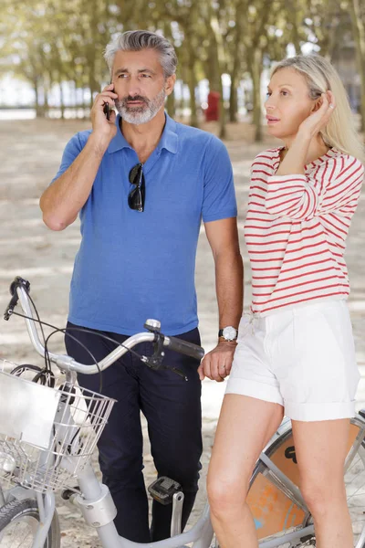 Volwassen man aan de telefoon met vrouw in het park — Stockfoto