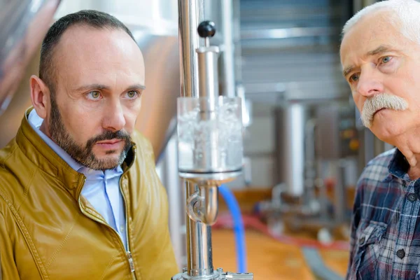 Närbild av män som observerar bryggeriprocessen — Stockfoto