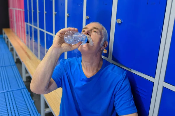 Muž pitná voda v šatně — Stock fotografie