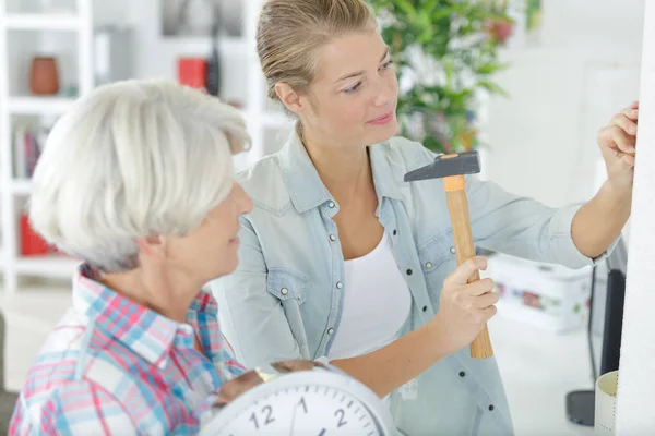 Woman holding a hammer and nails next to senior mum — ストック写真