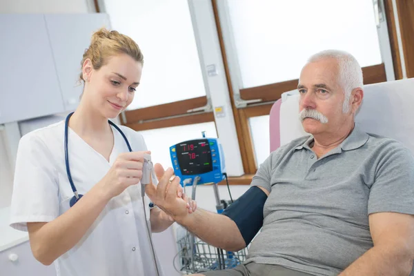 Doctora que muestra poner un dispositivo de pinchazo en el paciente — Foto de Stock
